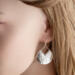  Side view of a person wearing a sterling silver hammered pear dangle earring, showcasing the design and ear wire.

